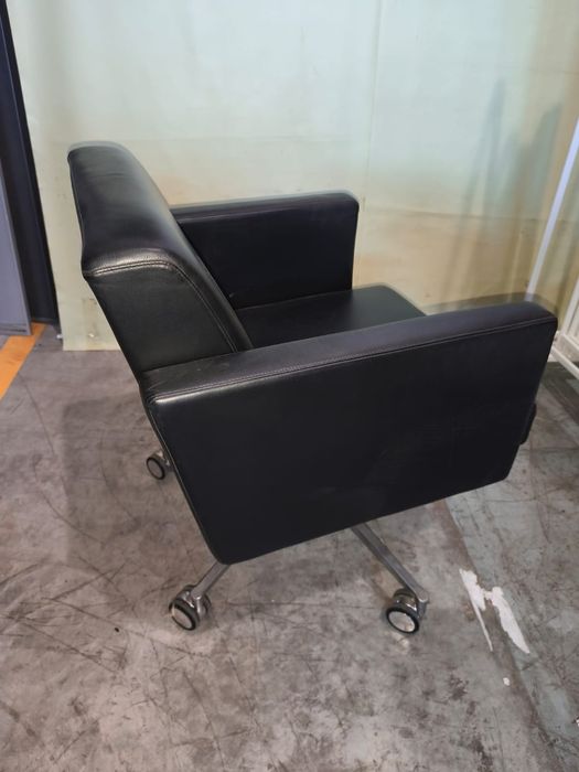 Cadeiras pretas, em couro e com rodas.