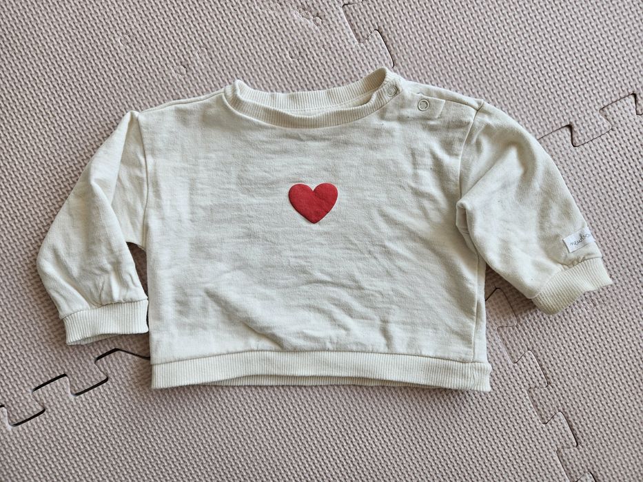 Beżowa bluza niemowlęca z czerwonym napisem.