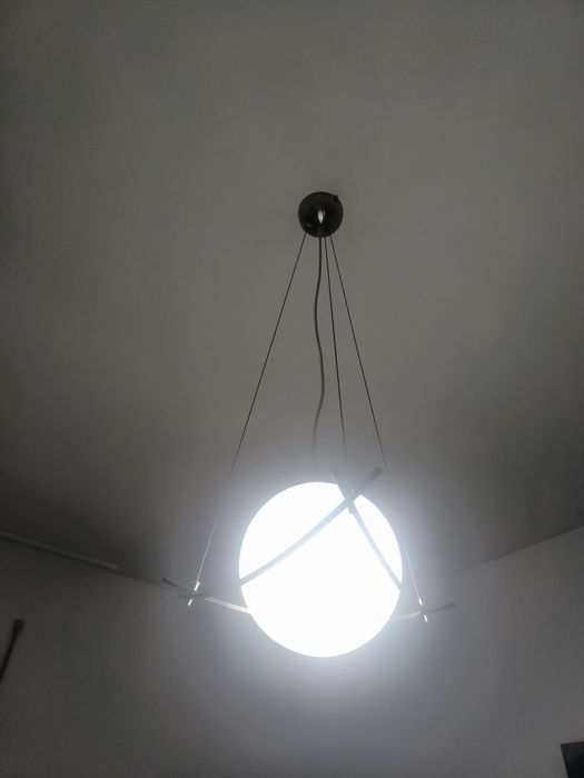 candeeiro suspenso com globo de vidro opalino e estrutura metálica curva, num estilo moderno