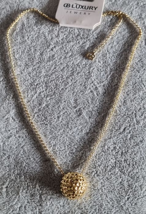 Colar dourado, em aço, com meia bola toda trabalhada. Tem extensor