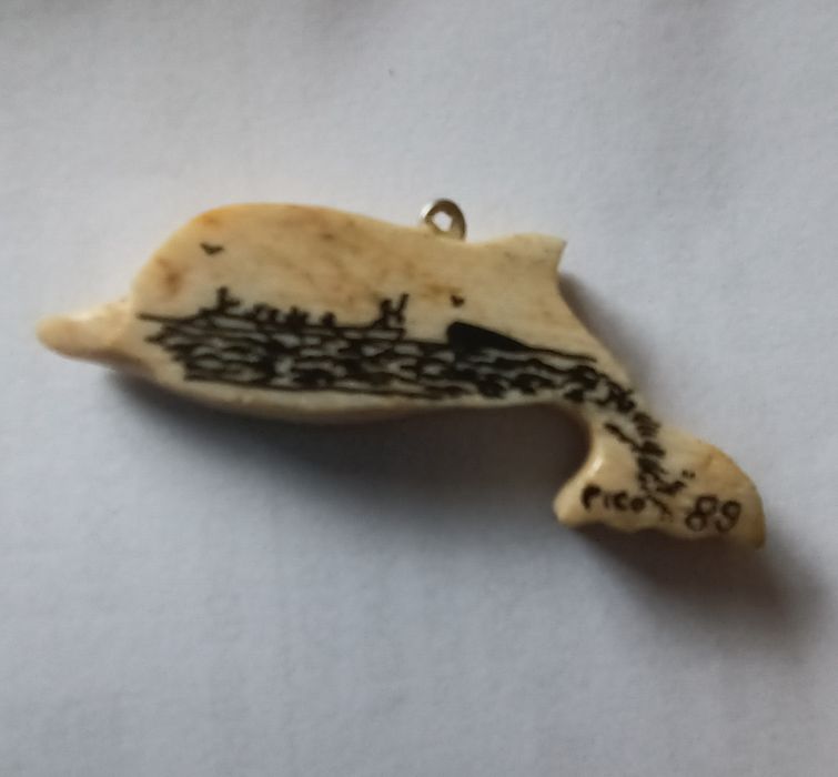 Golfinho  em osso de baleia.
Tem uma pintura alusiva à ilha do Pico. Data de 1989.
Mede aproximadamente 5 cm.
