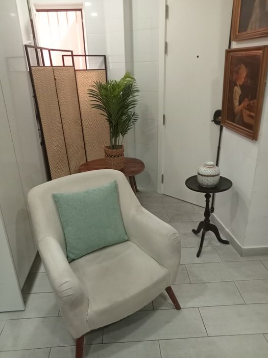 Cadeirão beige com almofada decorativa.