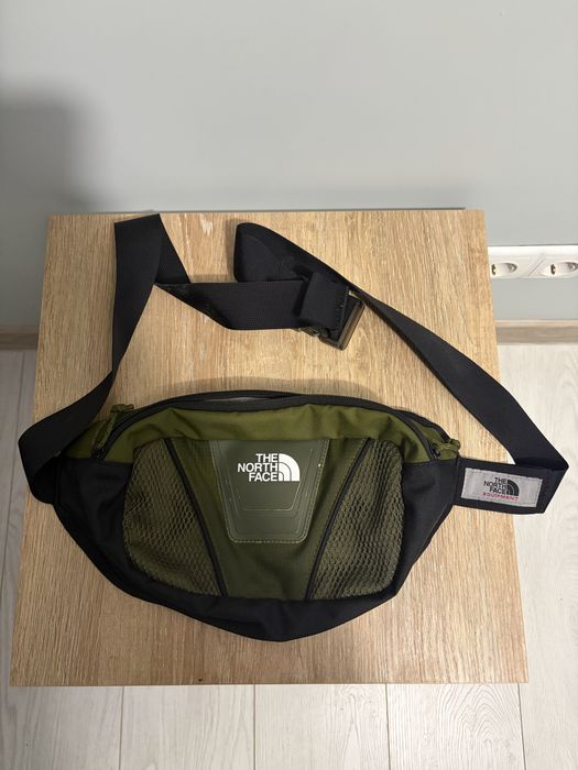 Оригінальна поясна сумка The North Face у стильному зеленому кольорі з чорними вставками.