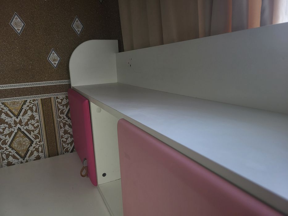 кутовий письмовий стіл для школяра з біло-рожевою надбудовою.