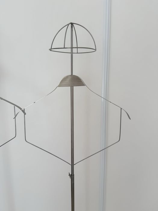 Cabide de pé, roupa e chapeu.