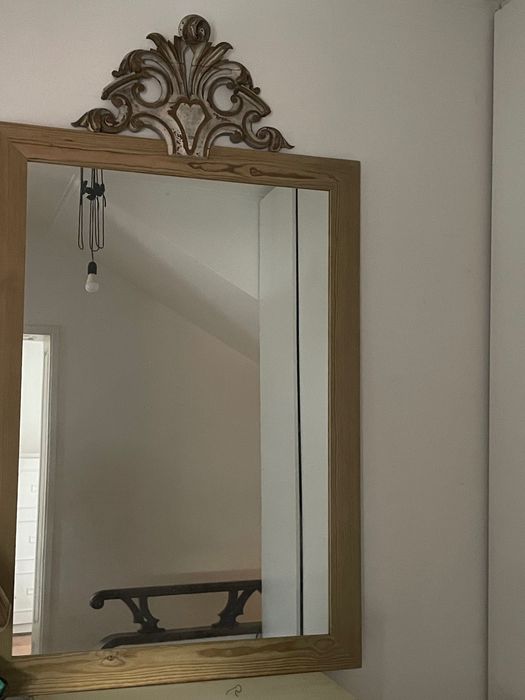 espelho antigo com moldura de madeira e frontão entalhado decorativo.