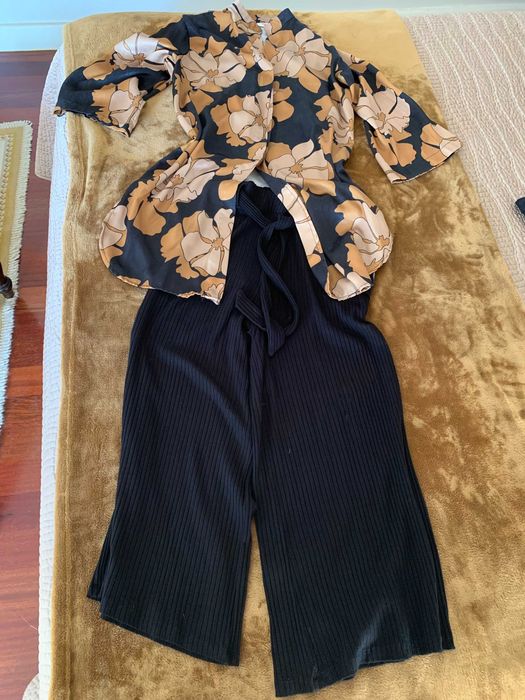 túnica de tecido acetinado e calças pretas largas