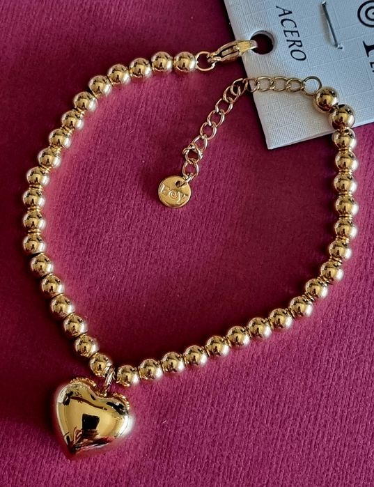 Pulseira dourada, em aço, toda às bolinhas e com 1 coração. Tem extens