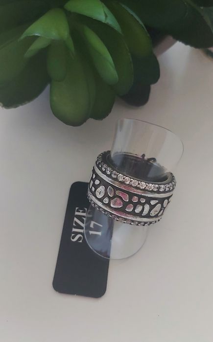 Anel prateado, em aço, com zirconias. Fundo preto. T17