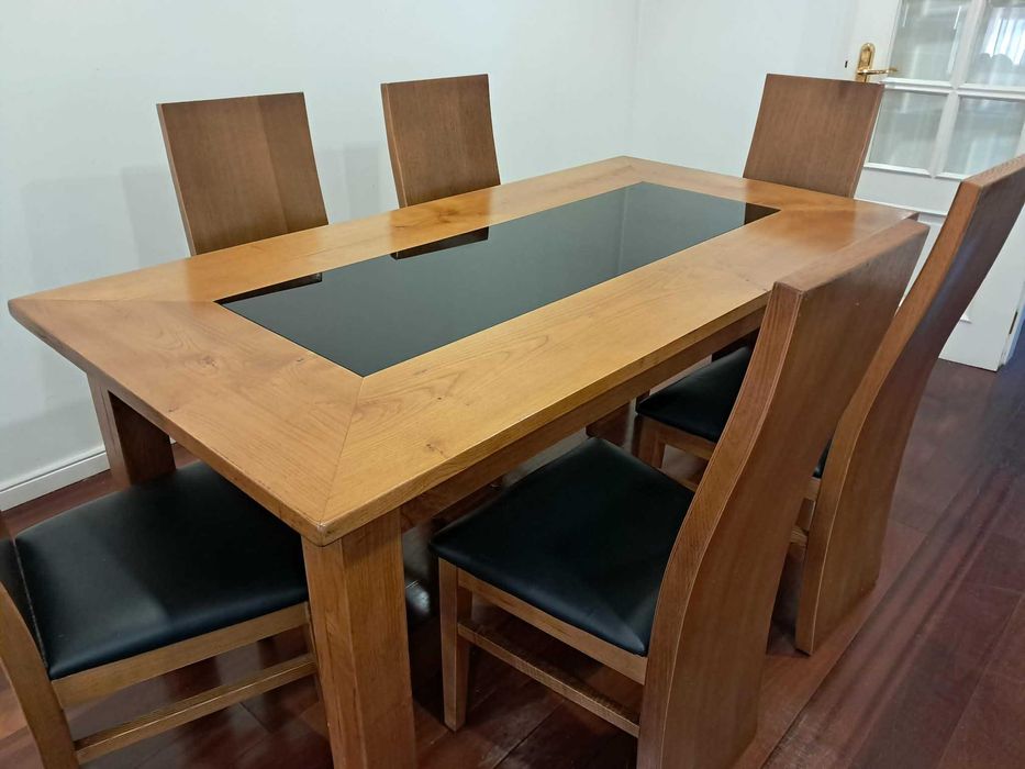Mesa madeira, com tampo parcial em vidro preto e 6 cadeiras com assento em pele. Oferta móvel a condizer