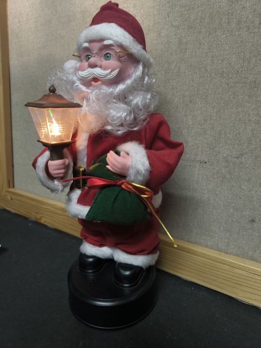 Pai Natal com candeeiro e saco de presentes com música.
Figura decorat