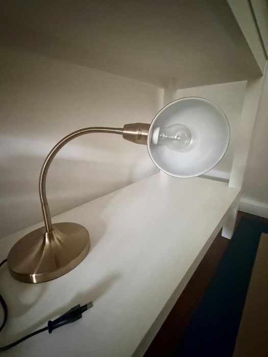 Candeeiro de secretária dourado, elegante e funcional.