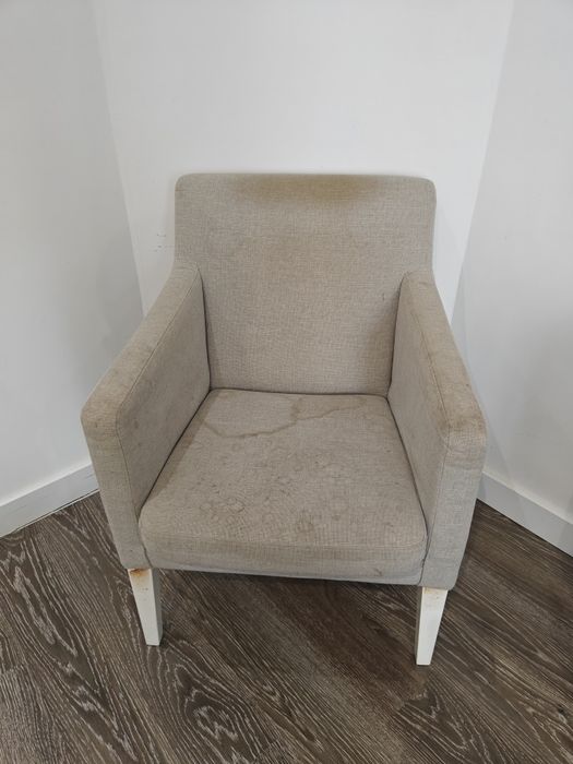 Poltrona de cor beje com pés brancos.