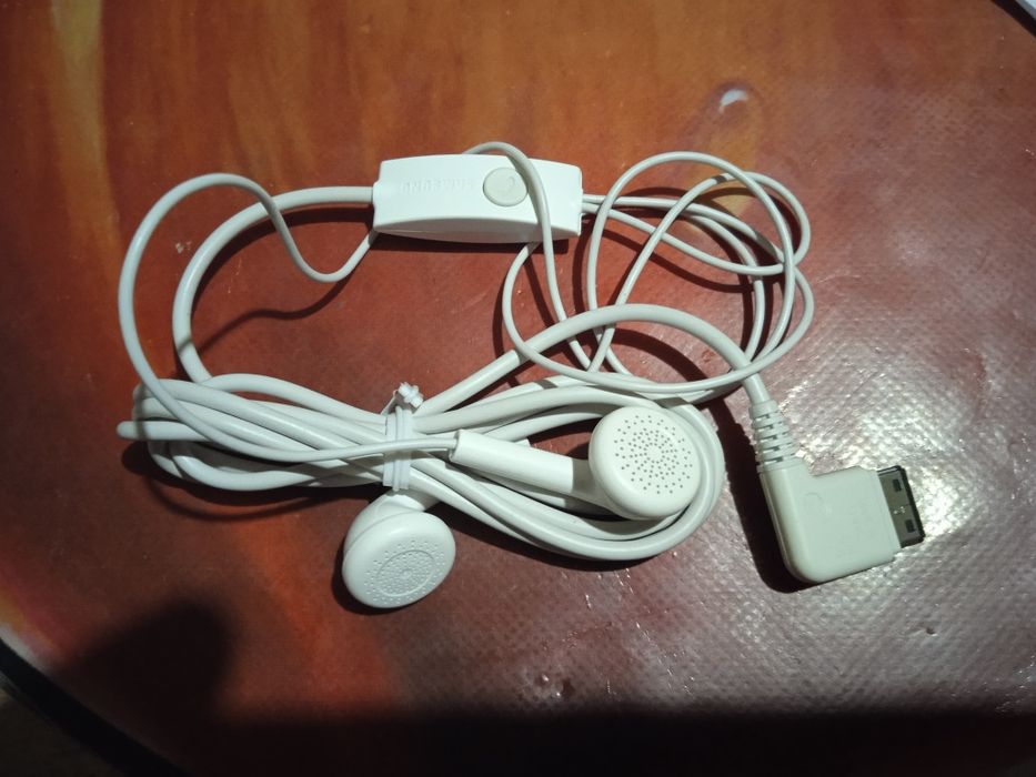 Білі дротові навушники з вбудованим пультом дистанційного керування.
В