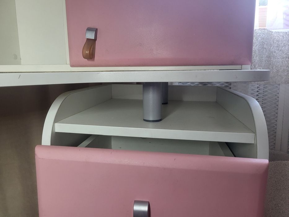 кутовий письмовий стіл для школяра з біло-рожевою надбудовою.