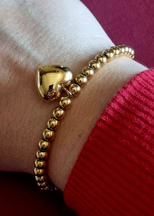 Pulseira dourada, em aço, toda às bolinhas e com 1 coração. Tem extens