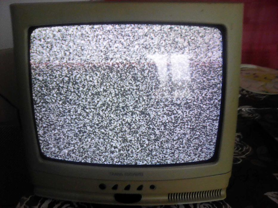 Televisão antiga a cores a funcionar, com comando e suporte de parede