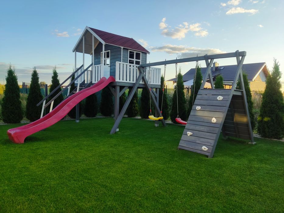 Duży drewniany domek dla dzieci ze zjeżdżalnią, huśtawkami, wspinaczką