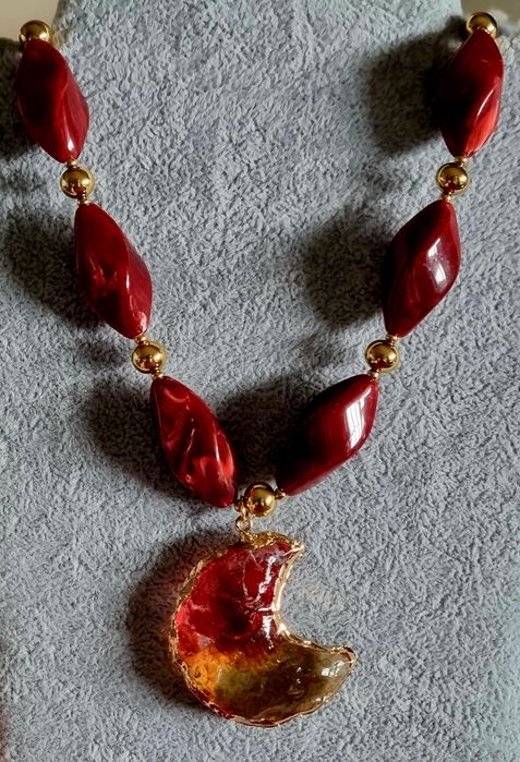 Colar dourado, em aço, com peças bordeaux em acrílico e uma meia lua.