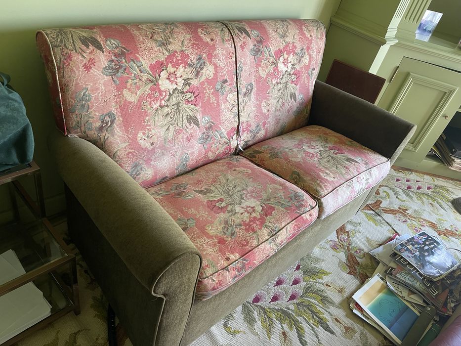Sofa de 2 lugares em verde e com padrao de flores rosa.