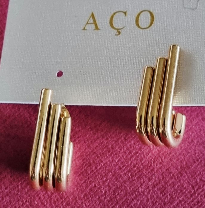 Brincos dourados, em aço, 3 "tubos" unidos de diferentes tamanhos. De pico