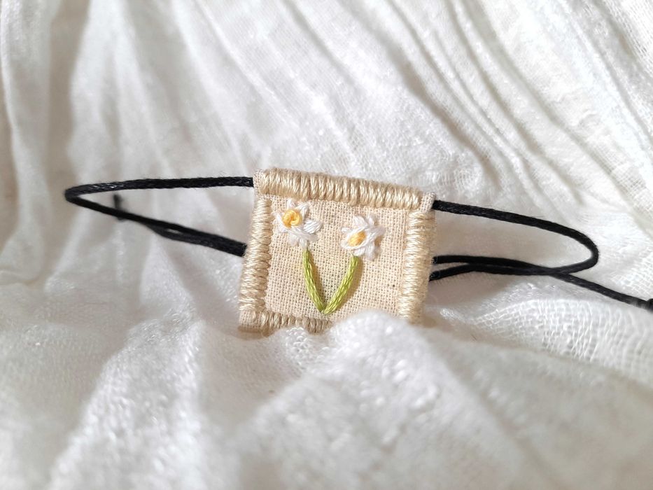 Pulseira bordada à mão com pingente de margarida branca