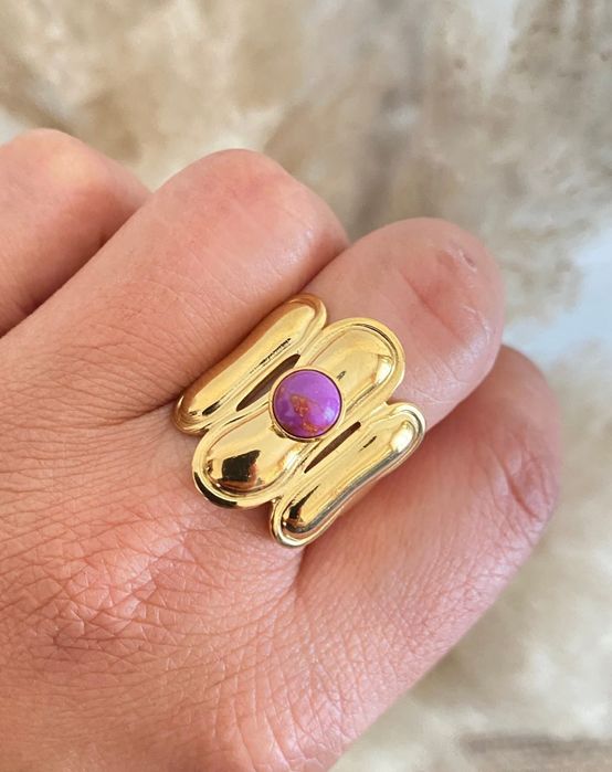 Anel dourado, em aço, com pedrinha redonda lilás. Ajustável