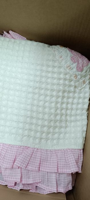 Manta de criança branca com folho e bonecos em cor de rosa . Tem umas