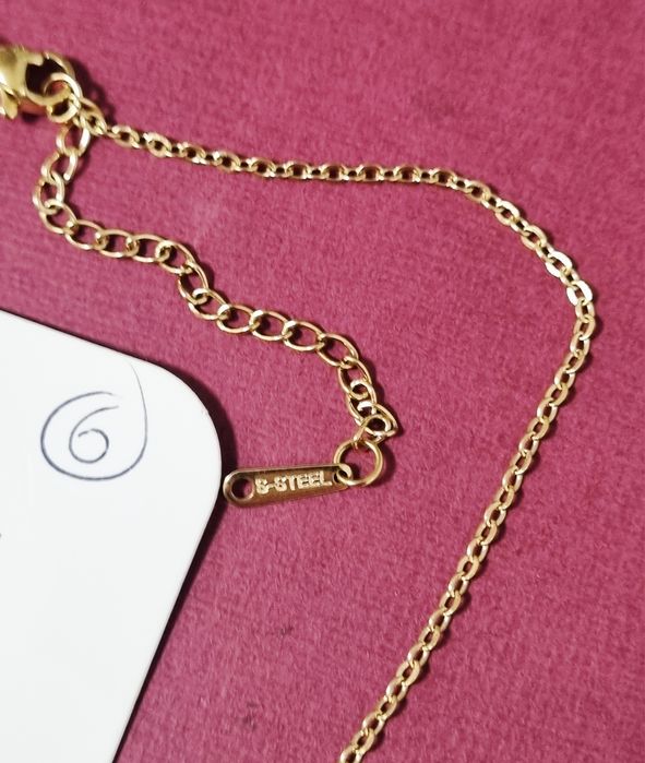 Colar dourado, em aço, com cruz colorida. Tem extensor