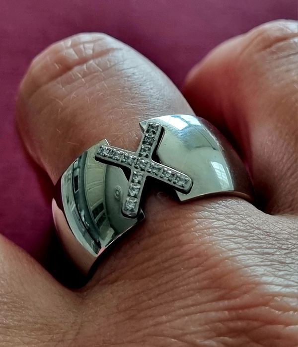 Anel grosso prateado, em aço, com um X em zirconias. T20