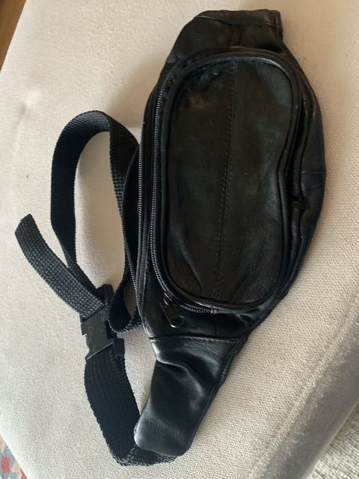 Bolsa de cabedal preta, é uma pochet classica de cintura com fecho.