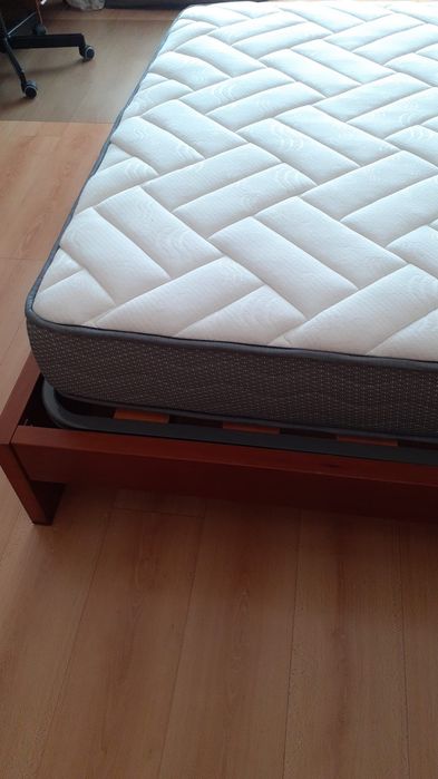 Cama de casal com uma mesa de cabeceira e colchão incluído
