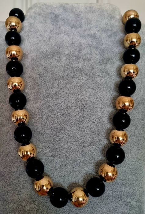 Colar dourado, em aço, às bolinhas douradas intercaladas com pretas. Leve.