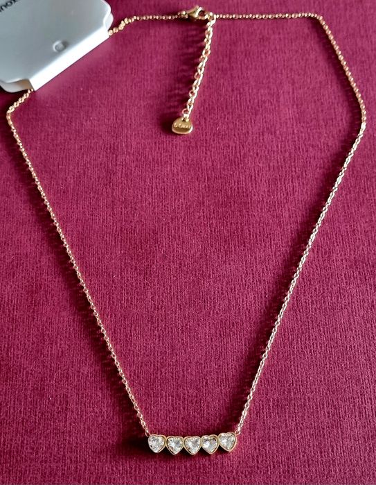 Colar dourado, em aço, com 5 pequenos corações em pedra de vidro.
