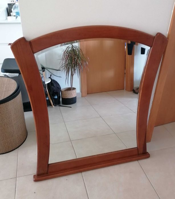 Um espelho com moldura de madeira, como novo