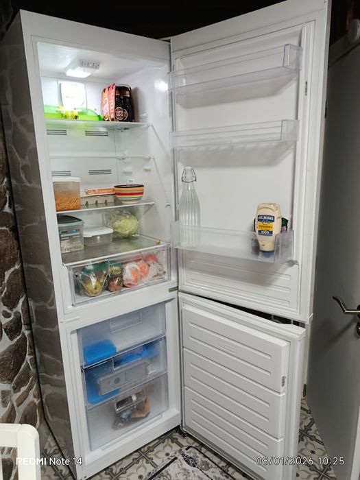 Um sofá cama, três Tvs e um refrigerador.
