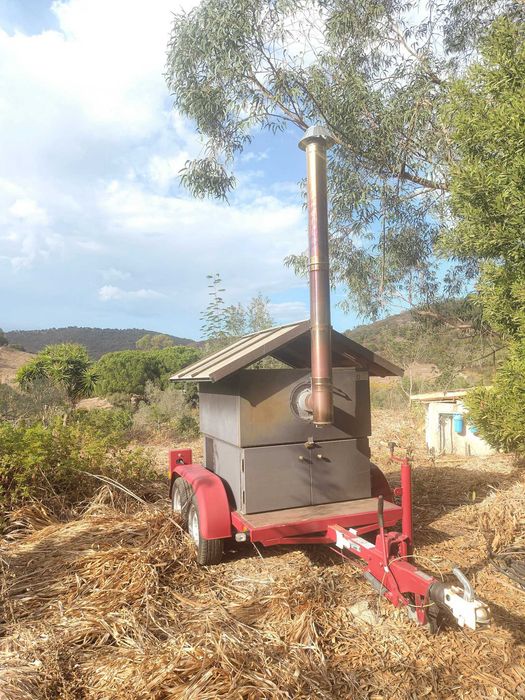 Forno de pedra a lenha profissional e móvel, montado sobre um chassis de reboque, concebido para eventos e utilização comercial em pequena escala.
