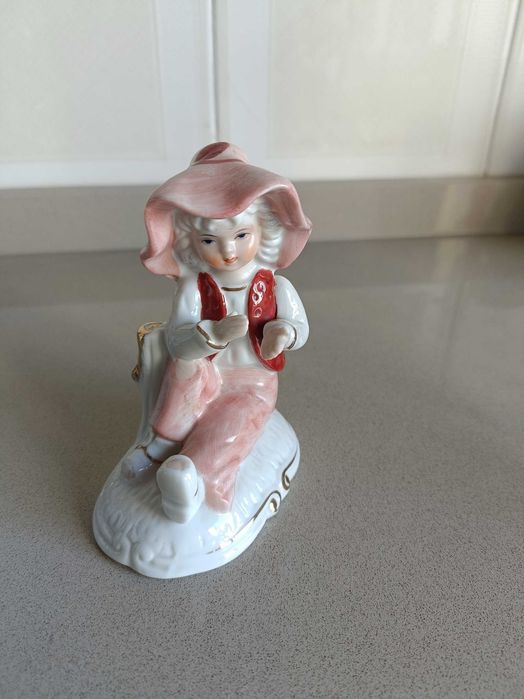 Decorative figurine of a boy wearing a hat and pink clothing