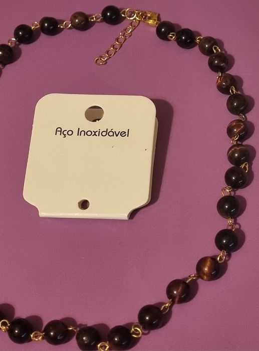 Colar dourado, em aço, às bolinhas castanhas de pedra natural "olho de gato". Tem extensor.
