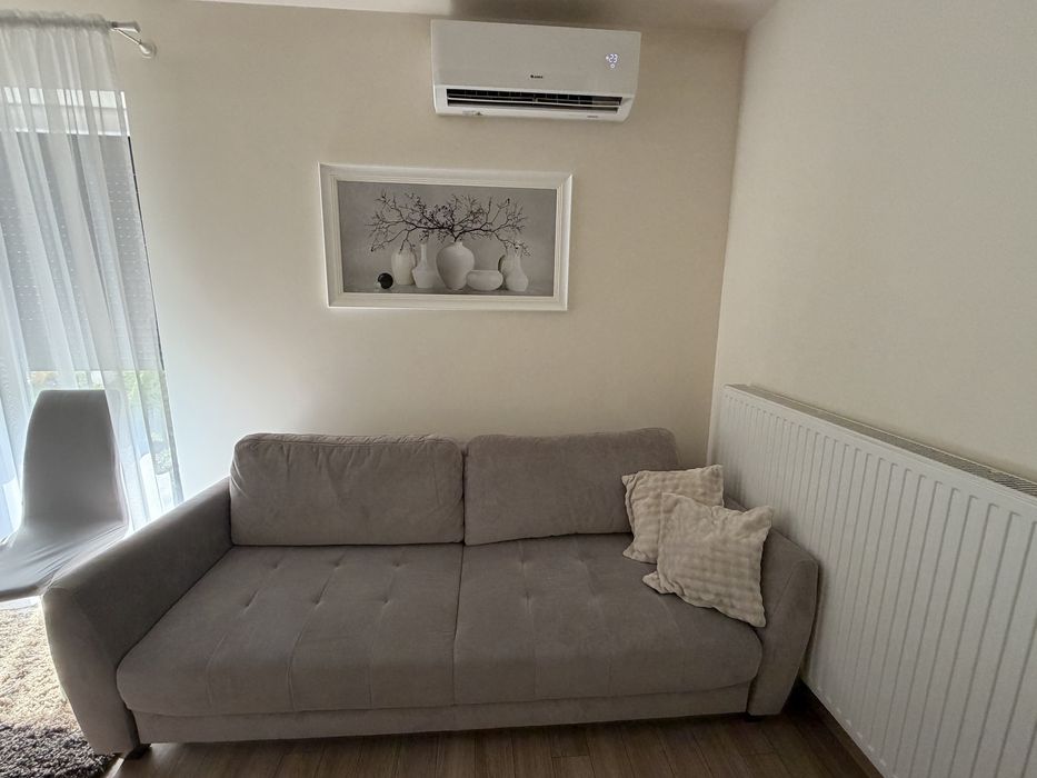 Szara sofa rozkładana z pojemnikiem na pościel
