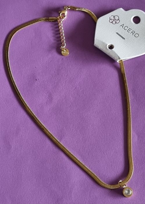 Colar dourado, em aço, malha fita com ponto de luz. Tem extensor