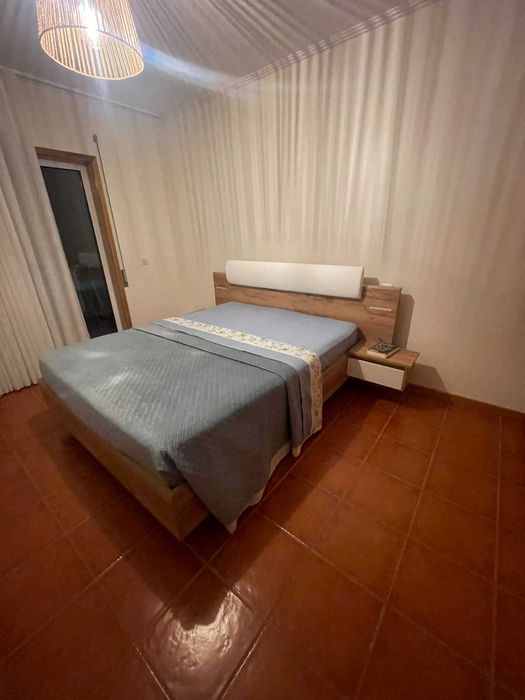 Cama de casal com mesas de cabeceira e iluminação