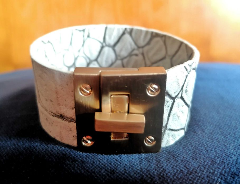 Pulseira em napa lavrada e metal dourado.