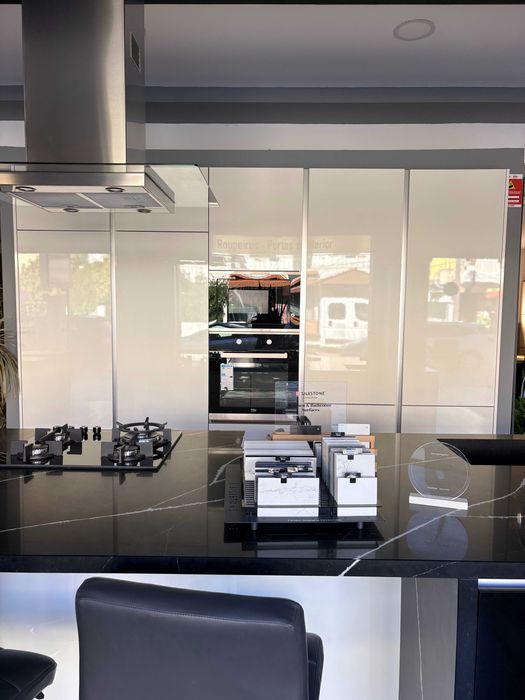 Cozinha de exposição com ilha — branco brilhante e tampo preto veiado