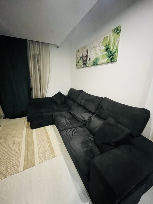 Sofá preto chaise longue, com arrumacão e 2 bancos