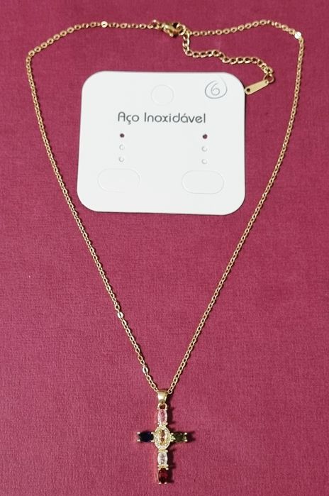 Colar dourado, em aço, com cruz colorida. Tem extensor