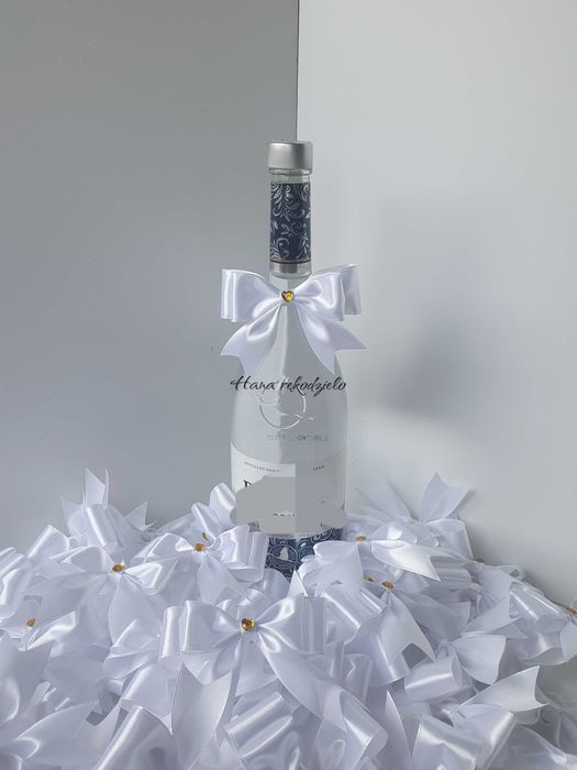 Białe kokardki ze złotym serduszkiem na alkohol