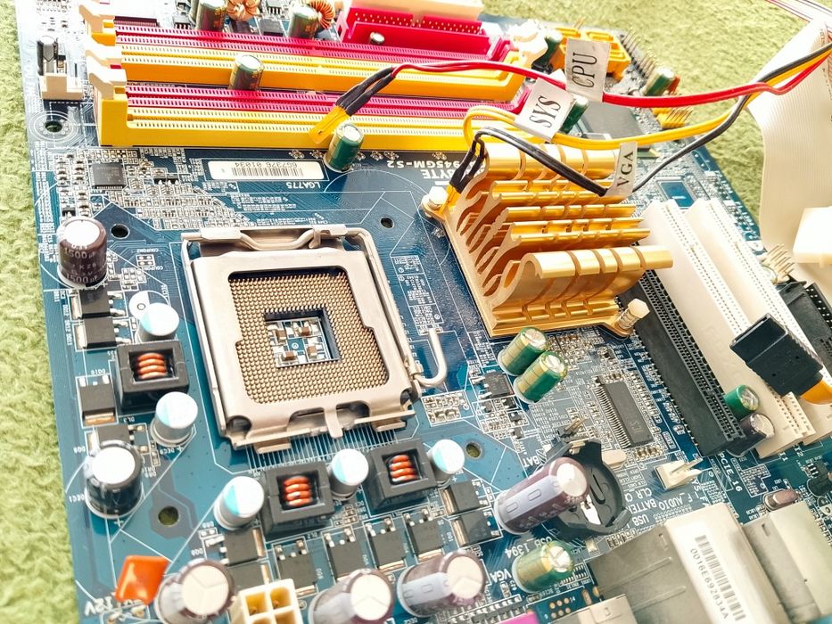 Płyta główna Gigabyte wraz z procesorem Intel Celeron głośniczkiem i kablami.