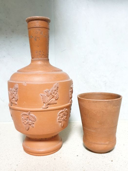 Antiga garrafa de água com copo em barro