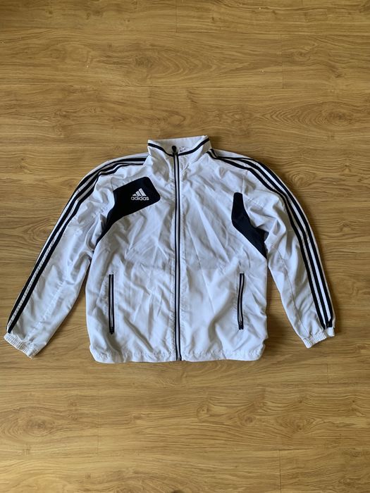 біла спортивна олімпійка adidas на блискавці доповнена чорними вставками на плечах та фірмовими смужками.